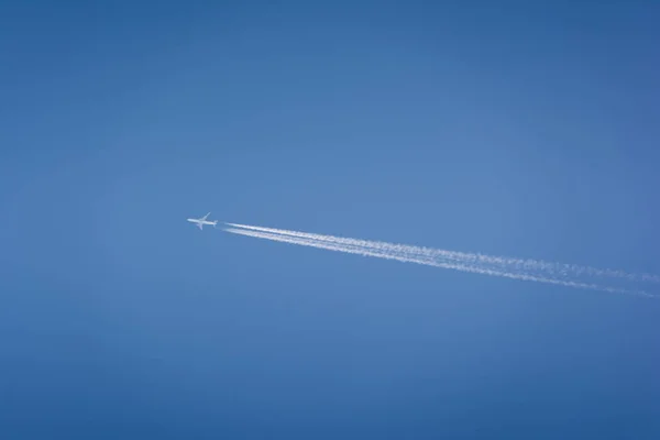 Avião voando alto no céu com trilhas de vapor — Fotografia de Stock