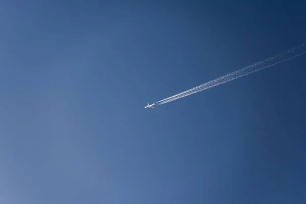 Avião voando alto no céu com trilhas de vapor — Fotografia de Stock