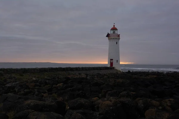 Port fairy lighthouse at sunrise with rocks