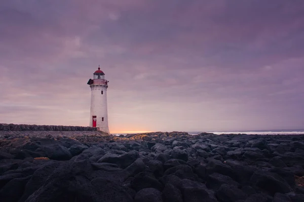 Port fairy lighthouse at sunrise with rocks