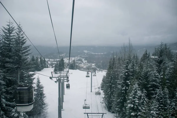 Télésiège de ski et télécabine montant la montagne enneigée entre — Photo