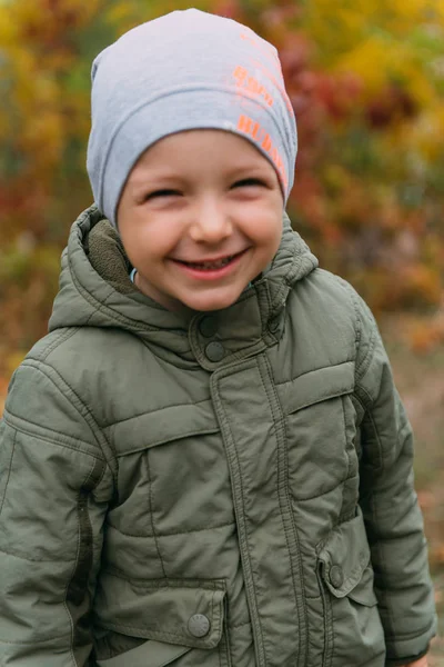 portret küçük çocuk bir yeşil ceket ve gülümseyen bir sonbahar forest park içinde gri şapka 