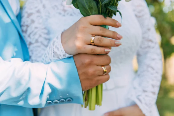 手上的新娘和新郎在花束上的结婚戒指 — 图库照片