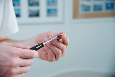 Adam bir tornavida elinde - beyaz deri, siyah ve sarı tornavida tutar. Evde kalıp işleri