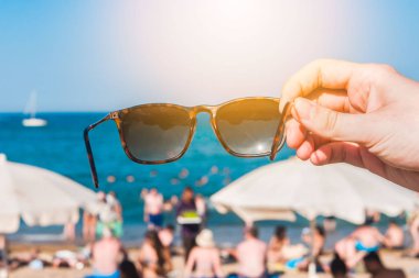 Sahilde, parlak yaz günü bir elinde güneş gözlüğü