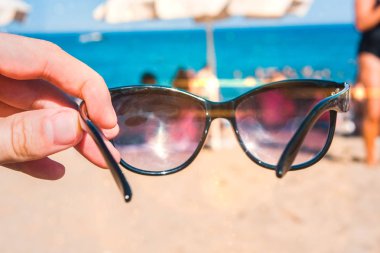 Sahilde, parlak yaz günü bir elinde güneş gözlüğü