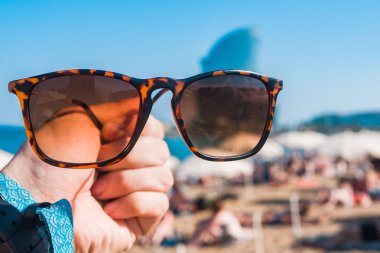 Sahilde, parlak yaz günü bir elinde güneş gözlüğü