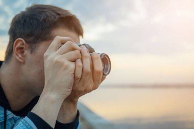 Gün batımında vintage film kameralı bir kot ceket bir adam