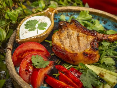 Et kemikte, sebzeler de el işi tabakta. Beyaz sos