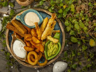 Bira için abur cubur tabağı. Patates kızartması, peynir çubuğu, soğan halkası ve beyaz sos