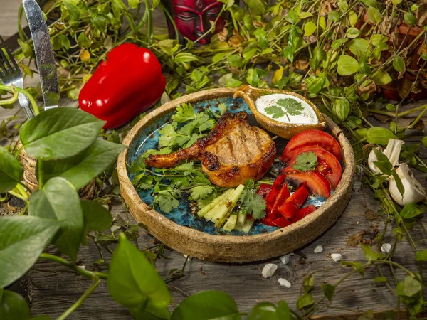 Viande sur l'os avec des légumes dans une assiette artisanale. Sauce blanche — Photo