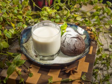 Lezzetli çikolatalı kekler üzerine pudra şekeri ve bir bardak süt serpilmiş.