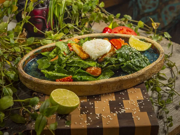 Ensalada sabrosa con huevo, tomate, salsa de guacamole, con galletas saladas, lima y hierbas en un plato artesanal —  Fotos de Stock