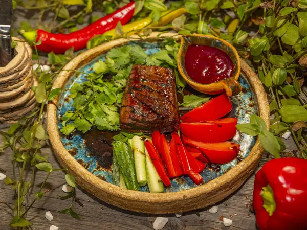 Delicioso filete de carne con verduras, tomate y pepino rebanado en tiras en platos artesanales —  Fotos de Stock