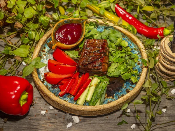 Delicioso filete de carne con verduras, tomate y pepino rebanado en tiras en platos artesanales —  Fotos de Stock