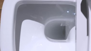 Beyaz otomatik tuvalet. Modern teknolojik çözüm. Tuvaletin kapağını ve kenarını kaldırıyorum..