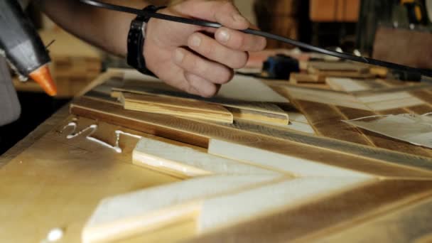 大工は ワークショップで合板にスラットを接着することによって木製パネルを作る — ストック動画