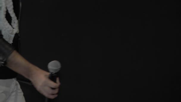 Rock star monte sur scène. Un homme vêtu d'une veste en cuir noir avec un microphone à la main .