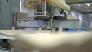 Büyük bir ahşap işçiliği makinesi ahşap bir üründe delikler açıyor. Elektronik kontrol, teknolojik üretim.