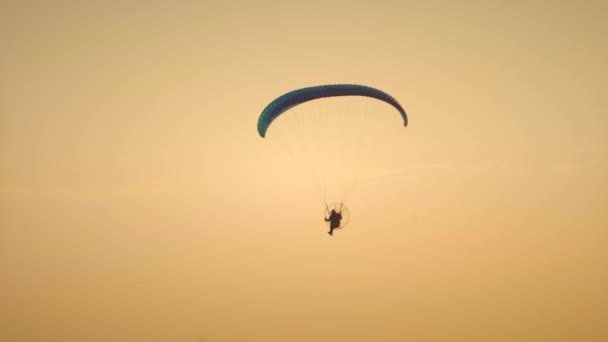 男は日没時に町のモーターでパラグライダーを飛ぶ — ストック動画
