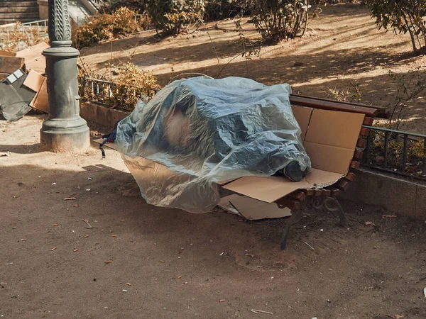 Hajléktalan Egy Parkban Alszik Egy Padon Műanyag Fólia Alatt Nap — Stock Fotó