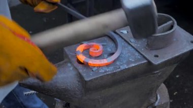 Bir demirci iş başında, sıcak metal dövüyor. Metal Atölyesi