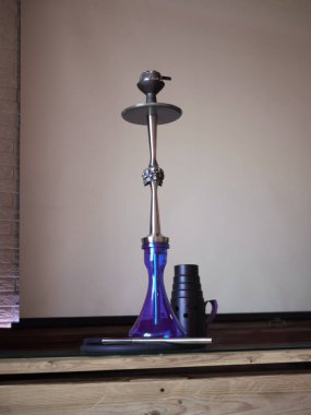 Kafe masasında güzel bir arka lambası olan yeni cam nargile.