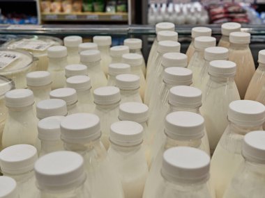 Süpermarketteki bir rafta şişe süt. Bir sürü şişe. Dükkan