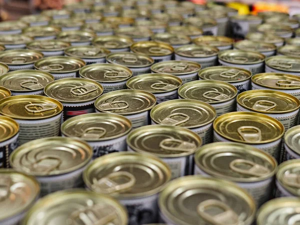 Iron cans with canned goods in a store on the counter. A lot of goods