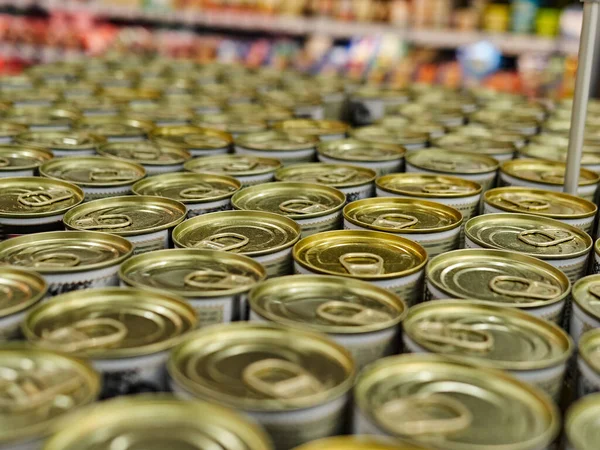 Iron cans with canned goods in a store on the counter. A lot of goods