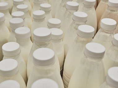 Süpermarketteki bir rafta şişe süt. Bir sürü şişe. Dükkan