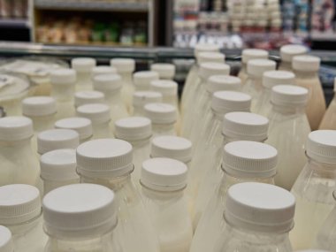 Süpermarketteki bir rafta şişe süt. Bir sürü şişe. Dükkan