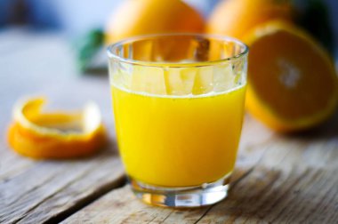 Ahşap masa üzerinde taze sıkılmış portakal suyu bir bardak