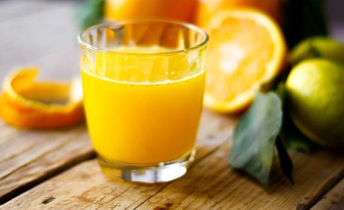 Ahşap masa üzerinde taze sıkılmış portakal suyu bir bardak