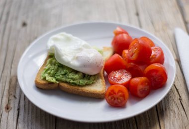 Beyaz plaka üzerinde domates ile avokado Tost üzerinde kızartılmış yumurta