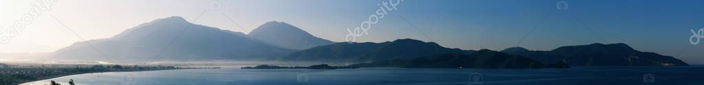 Panoramic photo. Morning sunrise landscape over the mountain range and the sea.