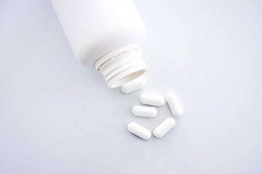 bir reçeteli ilaç şişesinden dökülüp beyaz kapsülleri