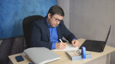 işadamı metin yazarak laptop ile masada oturan gözlüklü