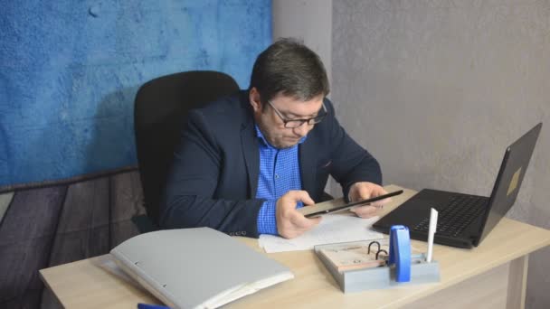 戴着眼镜的生意人坐在桌上用笔记本打字文字 — 图库视频影像