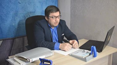 işadamı metin yazarak laptop ile masada oturan gözlüklü