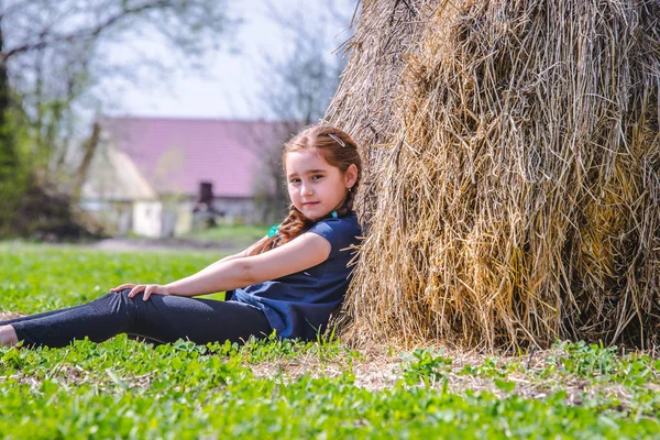 女の子 小麦の収穫後晴れた日の村でフィールドで干し草の山付近で遊んで おさげ髪 赤い髪の子 — ストック写真