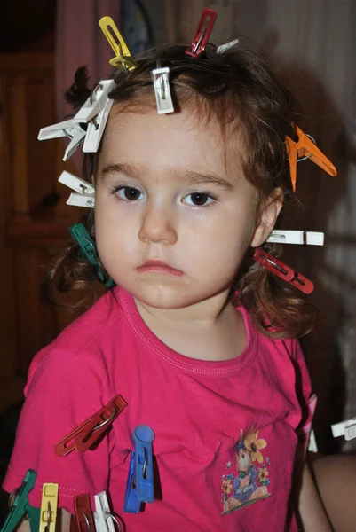 Child with clothes pegs in hair — Stock Photo, Image