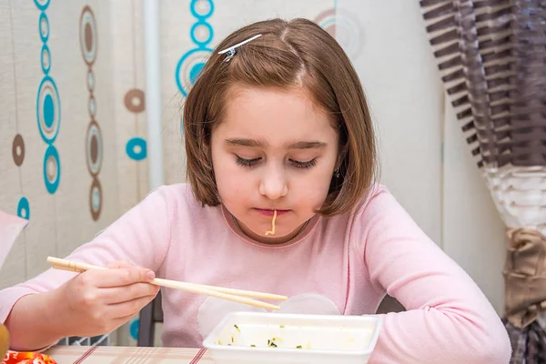 Child is eating Chinese noodles with chopsticks — Stock Photo, Image