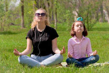 Anne ve kızı yeşil çimenlerin üzerinde dinlenmek