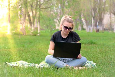 çimlerde oturan laptop ile kız