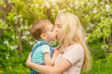 Anne hugs ve güneşli havalarda parkta bebek öpücük