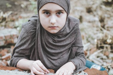 savaşta bir mülteci çocuk, harabeler üzerinde kirli bir yüzü olan Müslüman bir kız, barış ve savaş kavramı, çocuk ağlıyor ve yardım bekliyor.