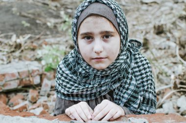 savaşta bir mülteci çocuk, harabeler üzerinde kirli bir yüzü olan Müslüman bir kız, barış ve savaş kavramı, çocuk ağlıyor ve yardım bekliyor.