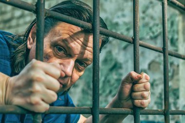 Depresyonda olan bir adam ellerini hapishane parmaklıklarında tutuyor. Suçun mahkumu. Kötü koşullar. Çığlık, umutsuzluk, acı, açlık.