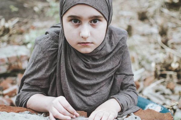 Un niño refugiado en la guerra, una niña musulmana con una cara sucia en las ruinas, el concepto de paz y guerra, el niño está llorando y esperando ayuda . —  Fotos de Stock